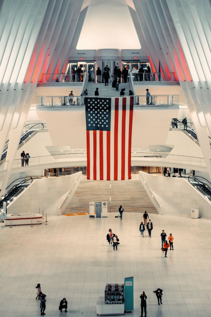 Spacious indoor atrium with a large American flag and multiple people interacting.